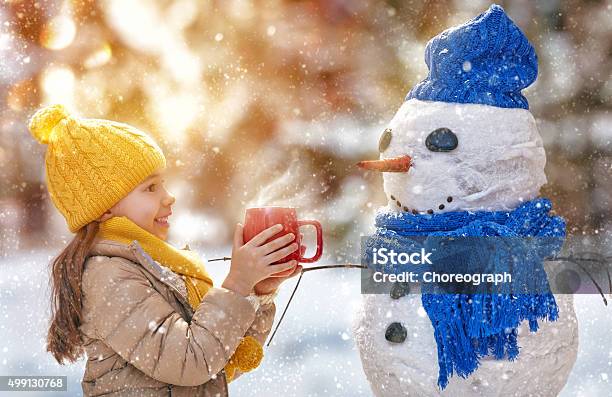 Girl Playing With A Snowman Stock Photo - Download Image Now - Christmas, Snowman, Child