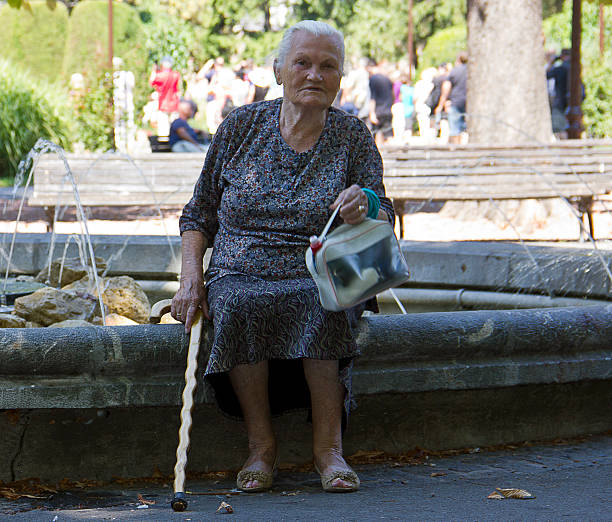 Belgrade, Serbia - August 30, 2015: A senior woman sitting near a fountain and there is People at Kalemegdan Fortress Park, Belgrade, Serbia. Belgrade is the capital city of Serbia and largest cities of Southeastern Europe.