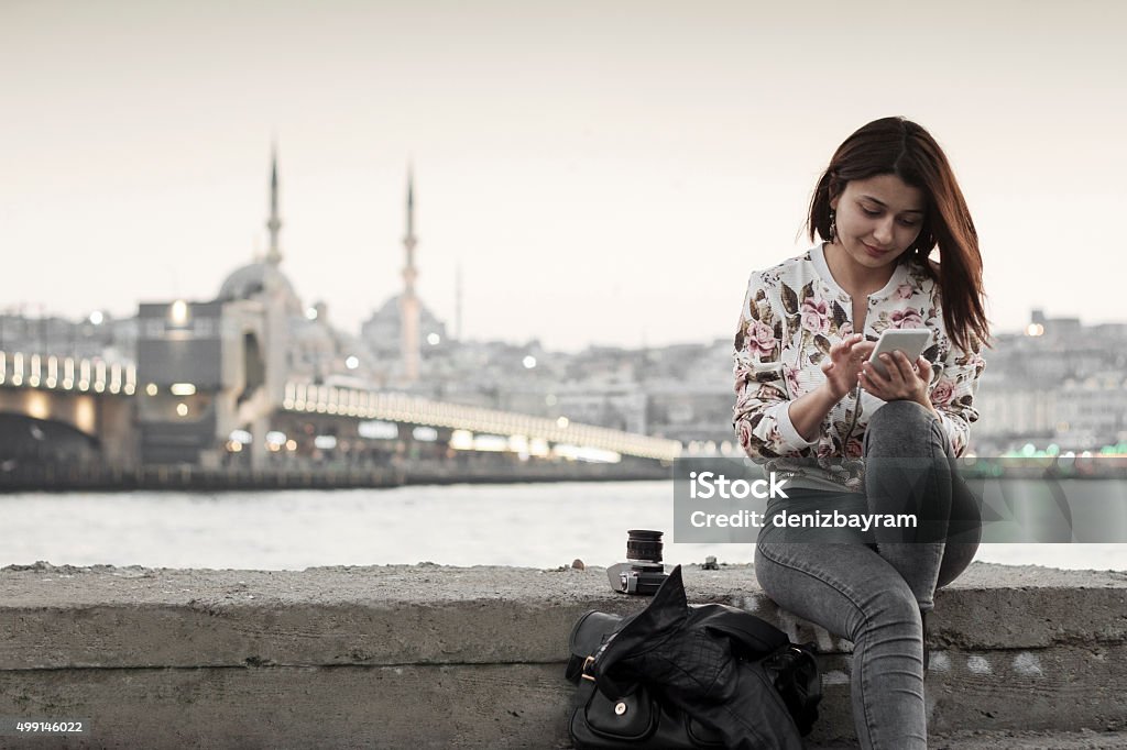 Pretty woman  using smart phone in Istanbul,Turkey Galata Bridge and Eminönü district in Istanbul,Turkey Türkiye - Country Stock Photo
