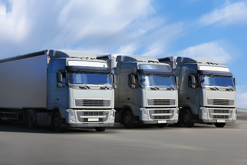 three trucks go on wide highway