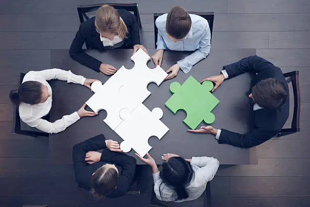 Photo of Business people assembling puzzle