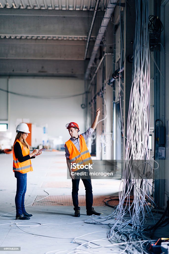 Engineers at construction site Engineers checking progress on electric installation setup Construction Industry Stock Photo