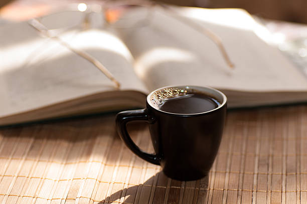 istock cup of coffee, standing next to an open book 499153456