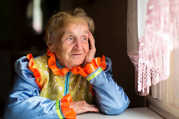 istock Elderly woman sadly looking out the window. 499153520