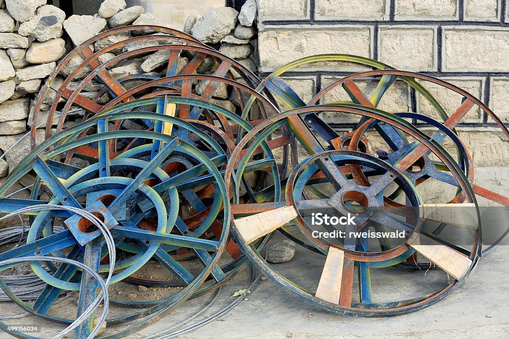 Iron wheels leaning on the wall. Sakya-Tibet. 1891 Iron wheels on stone and brick wall-town home on grounds of the 1288 AD-Sakya Sangpo and Chogyal Phagpa built South Seat of  Sakya-Grey Soil monastery, Left bank of Trum or Chong Chu river-Sakya-Tibet 2015 Stock Photo