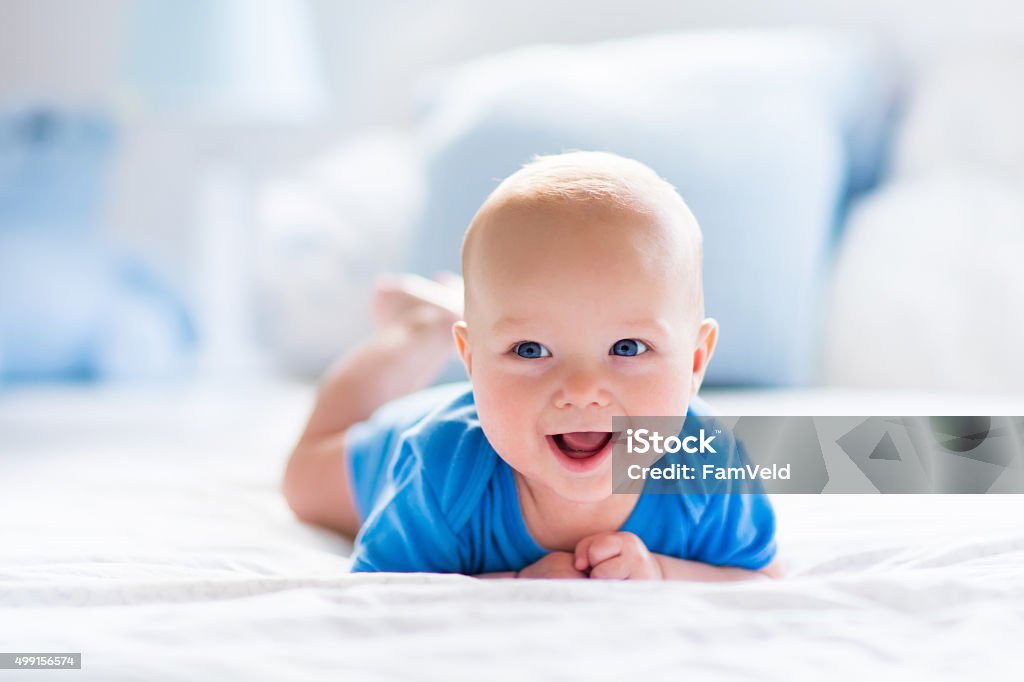 Baby boy in white sunny bedroom Adorable baby boy in white sunny bedroom. Newborn child relaxing in bed. Nursery for young children. Textile and bedding for kids. Family morning at home. New born kid during tummy time with toy bear. Baby - Human Age Stock Photo