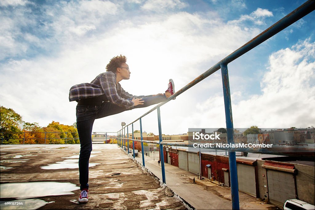 Young urban American black female stretching on Brooklyn rooftop Young urban American black female stretching on Brooklyn rooftop, looking ahead into the wind. Back lit by low sun. African-American Ethnicity Stock Photo