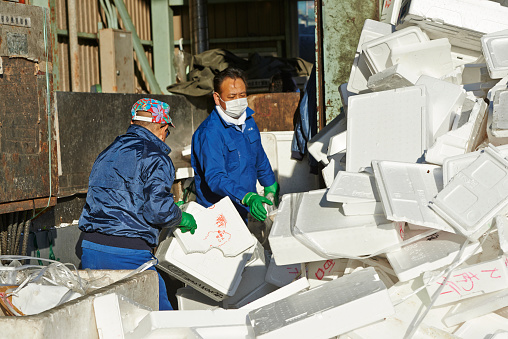 Tokyo, Japan - March 08, 2014: two japanese workers collect styrofoam boxes at a recycling center at Tsukiji Fish Market. Chuo Ward.