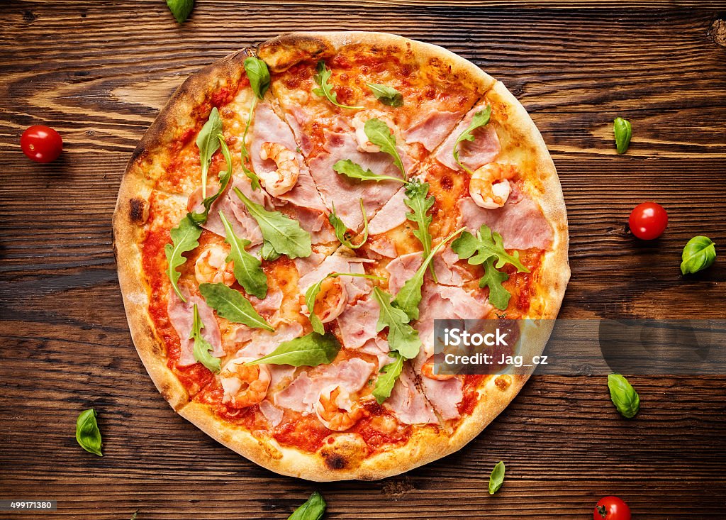 Delicious italian pizza served on wooden table Delicious italian pizza served on wooden table, shot from above 2015 Stock Photo