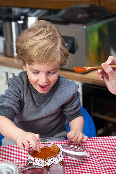 istock Hungry boy dips finger in jar of jam. 499172522