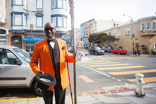 San Francisco, United States of America - November 22, 2015: A town troubador in an orange jacket asks for money after performing a song for bystanders. 