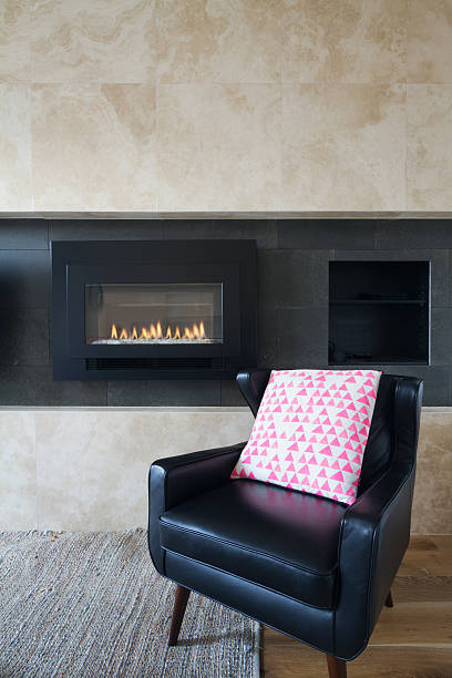 istock Black leather armchair and pink cushion next to fireplace 499177828