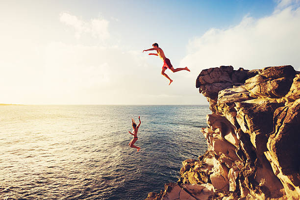 Summer Fun, Cliff Jumping Friends Cliff Jumping into the Ocean at Sunset, Outdoor Adventure Lifestyle fun vacations stock pictures, royalty-free photos & images