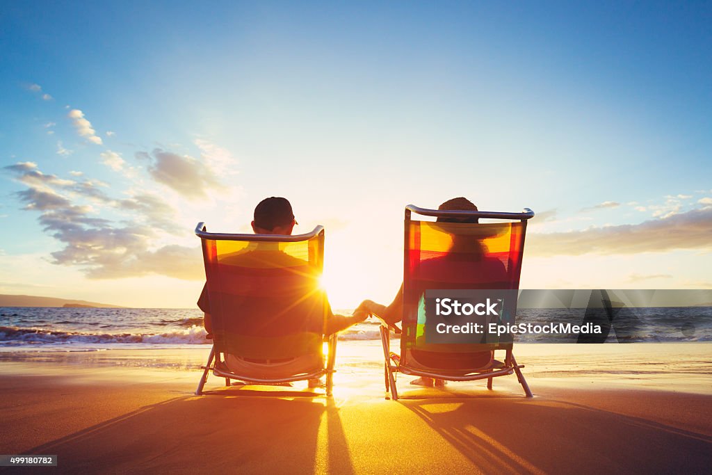 Retirement Vacation Concept, Mature Coupe Watching the Sunset Retirement Vacation Concept, Happy Mature Retired Couple Enjoying Beautiful Sunset at the Beach Beach Stock Photo