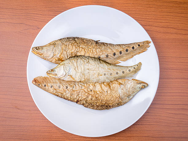 dry grilled smoked featherback fish dry grilled smoked featherback fish ( preserve food ) on white dish on wood background chitala stock pictures, royalty-free photos & images
