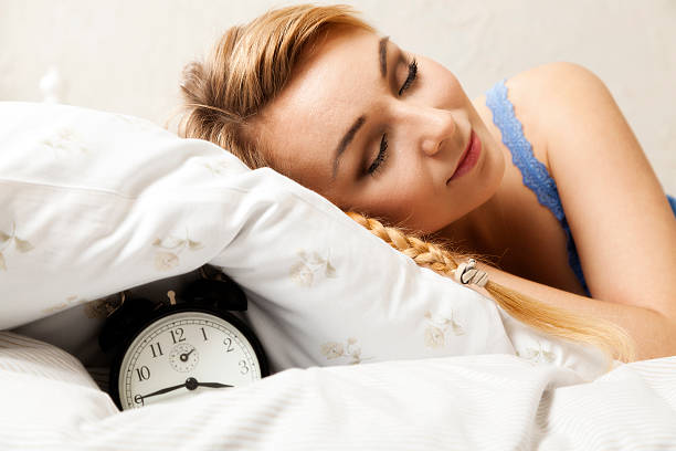 istock Beautiful young woman sleeping on bed with alarm clock 499191333