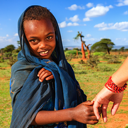 Caucasian female is holding young african child's hand in Ethiopian village.http://bem.2be.pl/IS/ethiopia_380.jpg