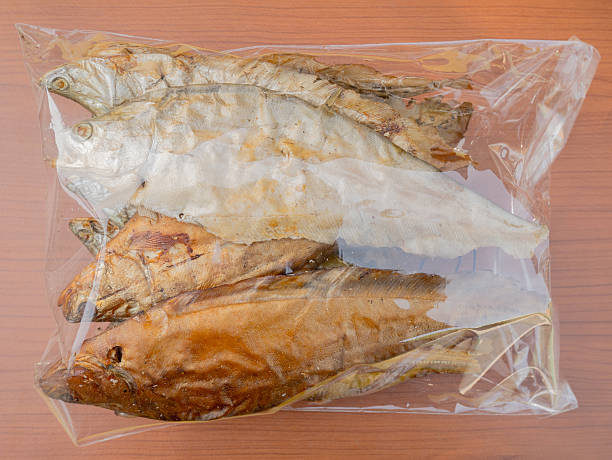 dry grilled smoked featherback fish dry grilled smoked featherback fish ( preserve food ) in plastic bag on wood background chitala stock pictures, royalty-free photos & images