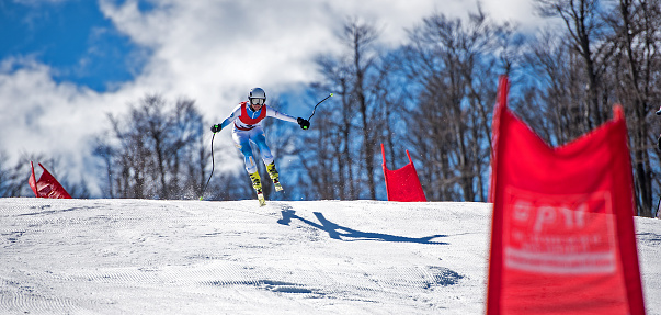 Professional alpine skier competing in an alpine skiing tournament or maybe just practicing, (giant) slalom or downhill, on a sunny day.