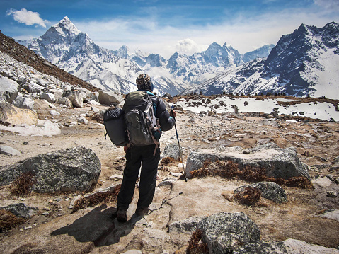 Trekker walking along the trail to Everest Base Camp with Ama Dablam and other Himalayan peaks in the background, Everest Region, Nepal.