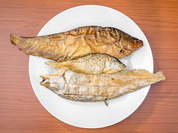 dry grilled smoked featherback fish dry grilled smoked featherback fish ( preserve food ) on white dish on wood background chitala stock pictures, royalty-free photos & images