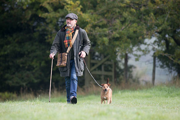 Man walking his dog in the field on a cold foggy morning.