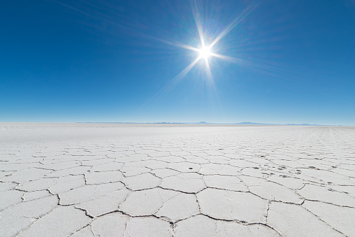 Wide angle view of the world famous Uyuni Salt Flat, among the most important travel destination in the Bolivian Andes. Close up of hexagonal shapes of the salt pans in backlight.