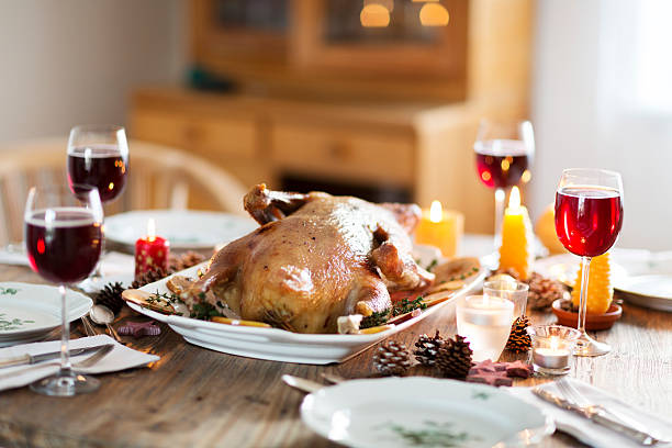 Festive christmas table with fried goose on a plate, festive decoration: burning candles, pine cone cones and stars 