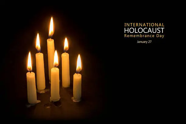 Six burning candles against black background, text International Holocaust Remembrance Day, January 27