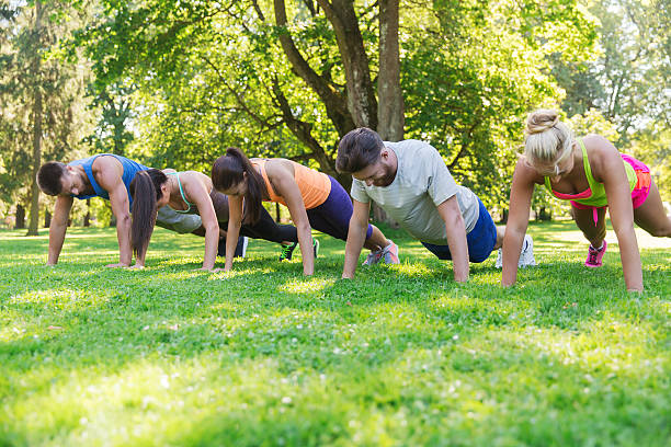 group of friends or sportsmen exercising outdoors fitness, sport, friendship and healthy lifestyle concept - group of teenage friends or sportsmen exercising and doing push-ups at boot camp fitness boot camp stock pictures, royalty-free photos & images