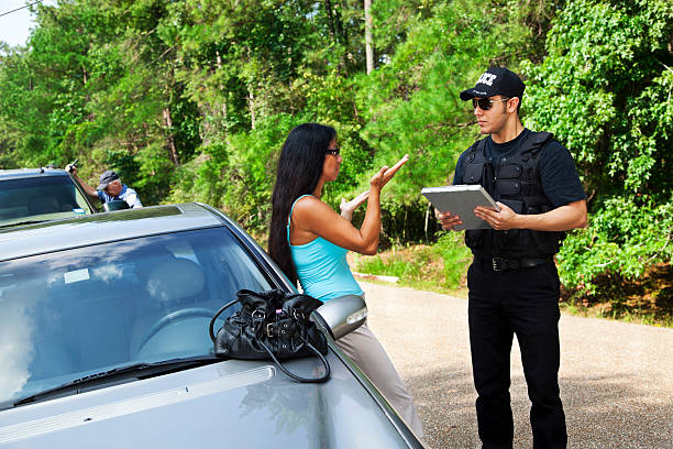 Crime: Policeman makes traffic stop. Woman explaining. Officer background.