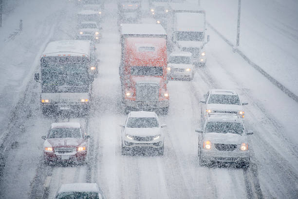 Driving in a Snow Storm Several vehicles are traveling slowly down a multi lane road on an icy stormy day. blizzard photos stock pictures, royalty-free photos & images