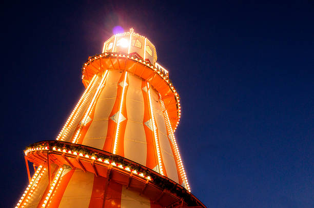 Illuminated Generic Helter Skelter at Night An illuminated generic yellow and orange helter-skelter attraction, shot at night time against a clear dark blue sky. hogmanay photos stock pictures, royalty-free photos & images