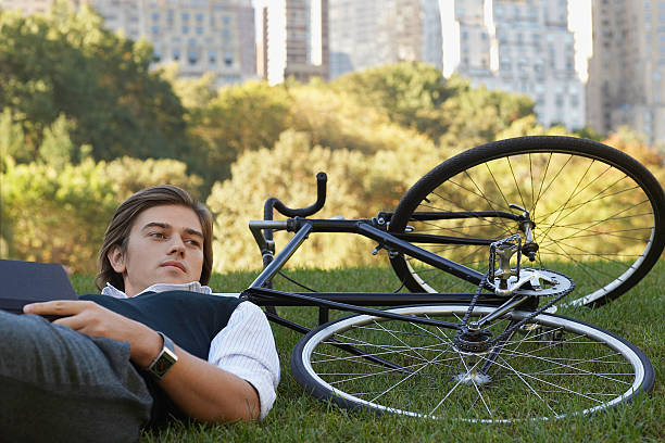 istock Businessman Lying Down On Bicycle In Park 499229357