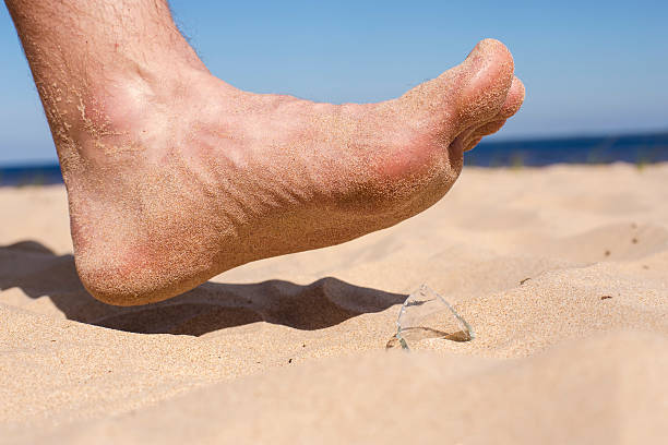 istock man on beach risk of stepping on broken bottle glass 499232382