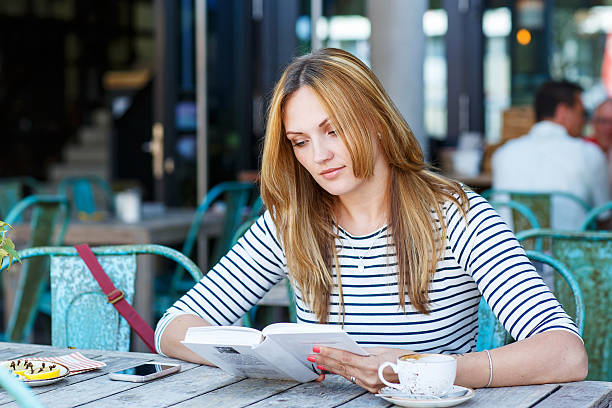istock Woman drinking coffee and reading book in cafe 499233958