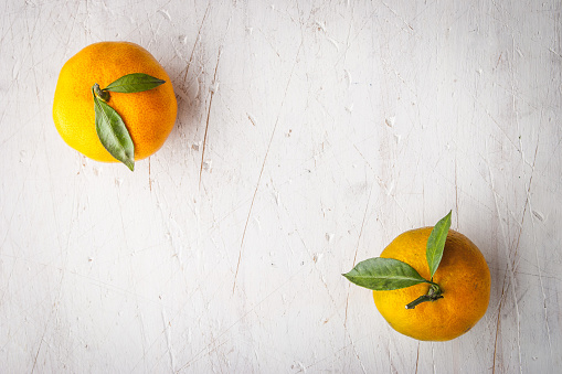 Two mandarins on the white wooden scratched table top view horizontal