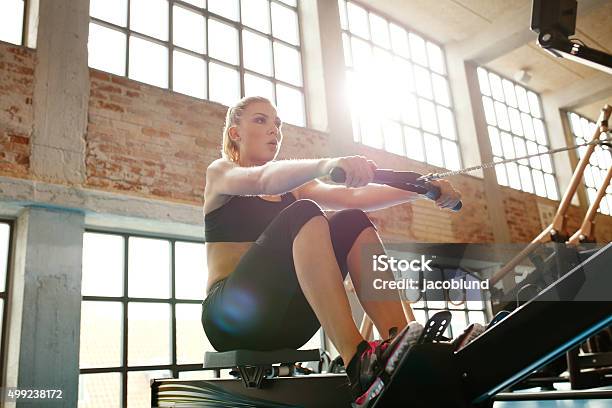 Young Woman Doing Exercises On Fitness Machine Stock Photo - Download Image Now - Rowing Machine, Gym, Women