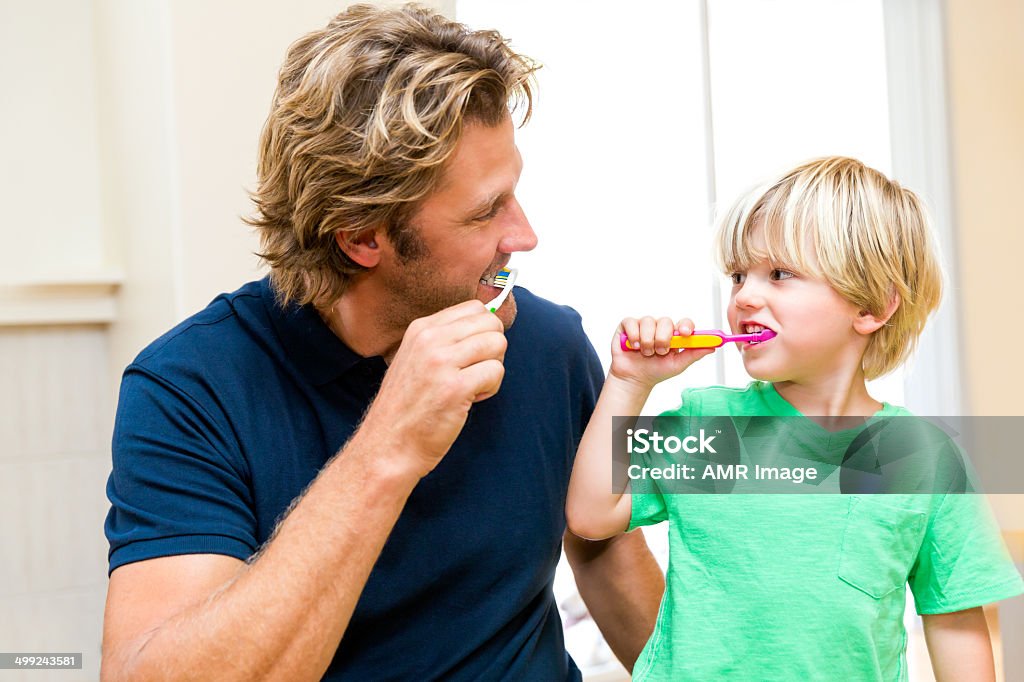 Father and son brushing teeth together. Father and son brushing teeth. Brushing Teeth Stock Photo