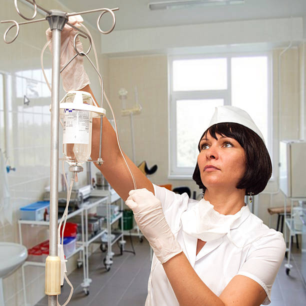 красивая медсестра готовит для проведения капельница для внутривенного введе�ния препарата - infused oil iv drip nurse hospital стоковые фото и изображения