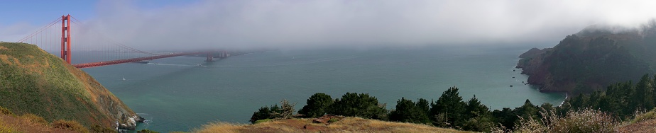 Panoramic of the Golden Gate Bridge with people and traffic crossing.