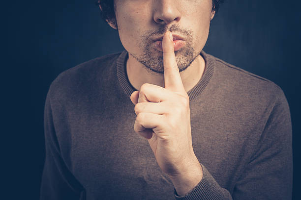 istock Young man with his finger on his lips 499247871