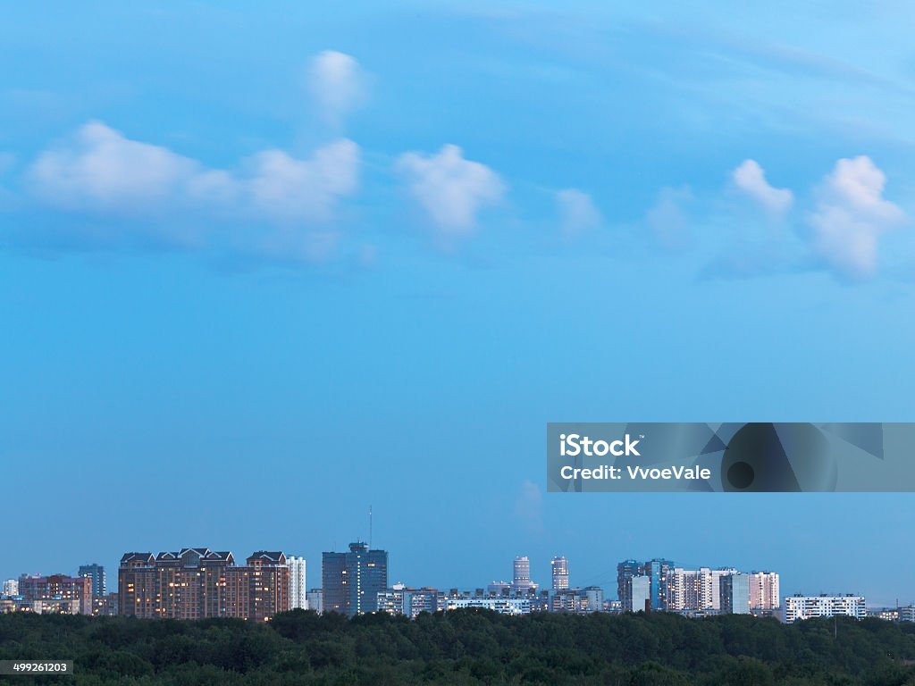 little white clouds in blue dusk sky over city little white clouds in blue dusk sky over city in summer evening Apartment Stock Photo