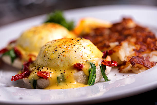 Eggs Benedict Fancy eggs benedict with sun dried tomatoes and spinach, coffee and orange juiceFancy eggs benedict with sun dried tomatoes and spinach, coffee and orange juice hollandaise sauce stock pictures, royalty-free photos & images