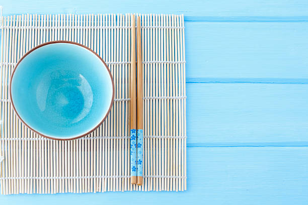bowl for sushi and sticks on clean blue table