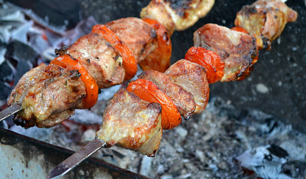 istock Barbecue shashlik with meat and tomatoes being grilled 499276367