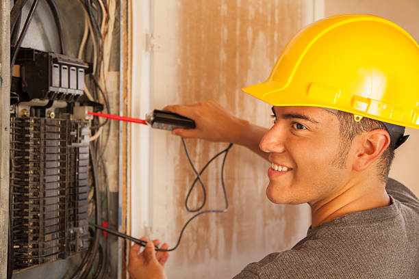 Construction: Blue collar worker, electrician repairs circuit breaker. Latin electrician tests the circuit breaker in a new home under construction. electrician smiling stock pictures, royalty-free photos & images