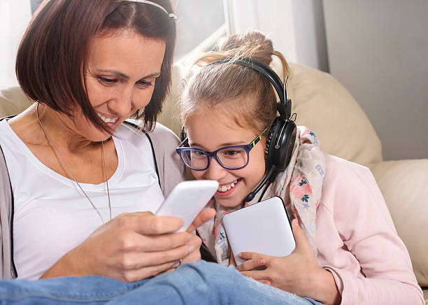 istock Happy mother and daughter on the couch using smartphone 499279716