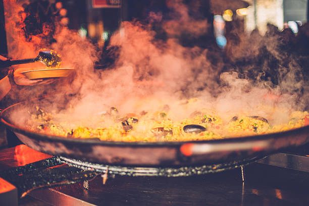 Seafood Paella in a Pan at Camden Market, London, UK Seafood paella in a pan being cooked in Camden Market, London, England, Wooden spoon and plate on the left. Nikon D800, full frame, XXXL. camden market stock pictures, royalty-free photos & images