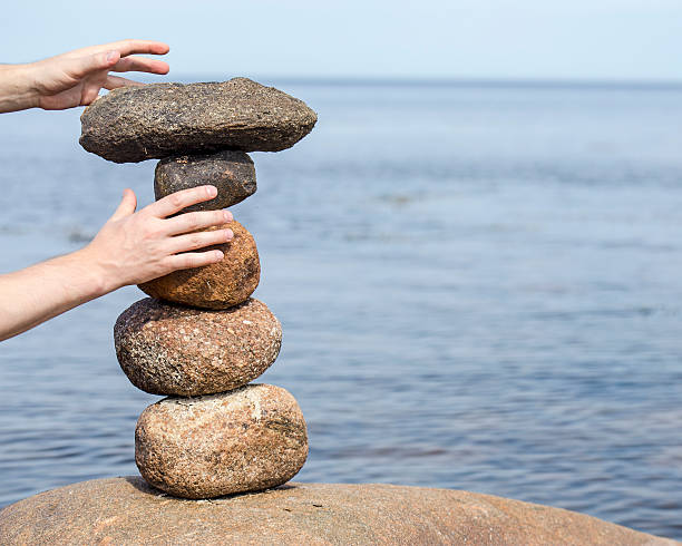 istock human hand making stack of round stones near water 499281696